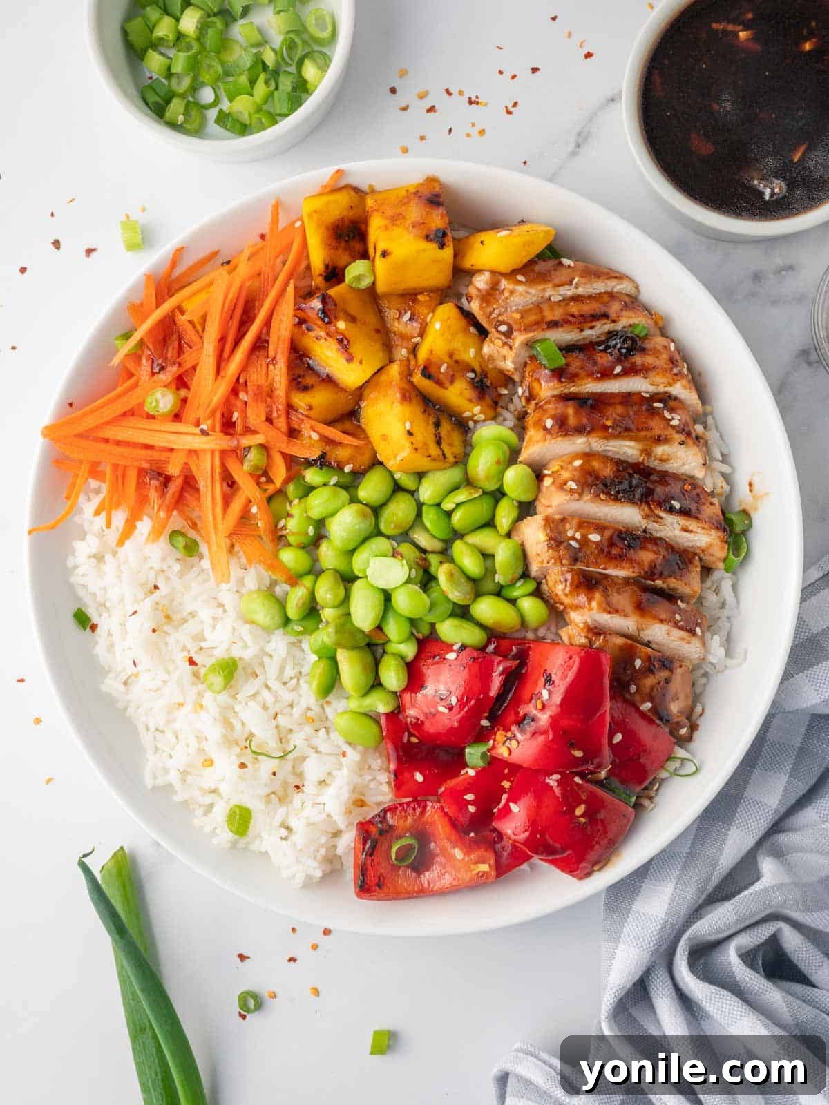A vibrant rice bowl topped generously with golden-brown teriyaki chicken, various colorful vegetables, and a glossy teriyaki sauce.