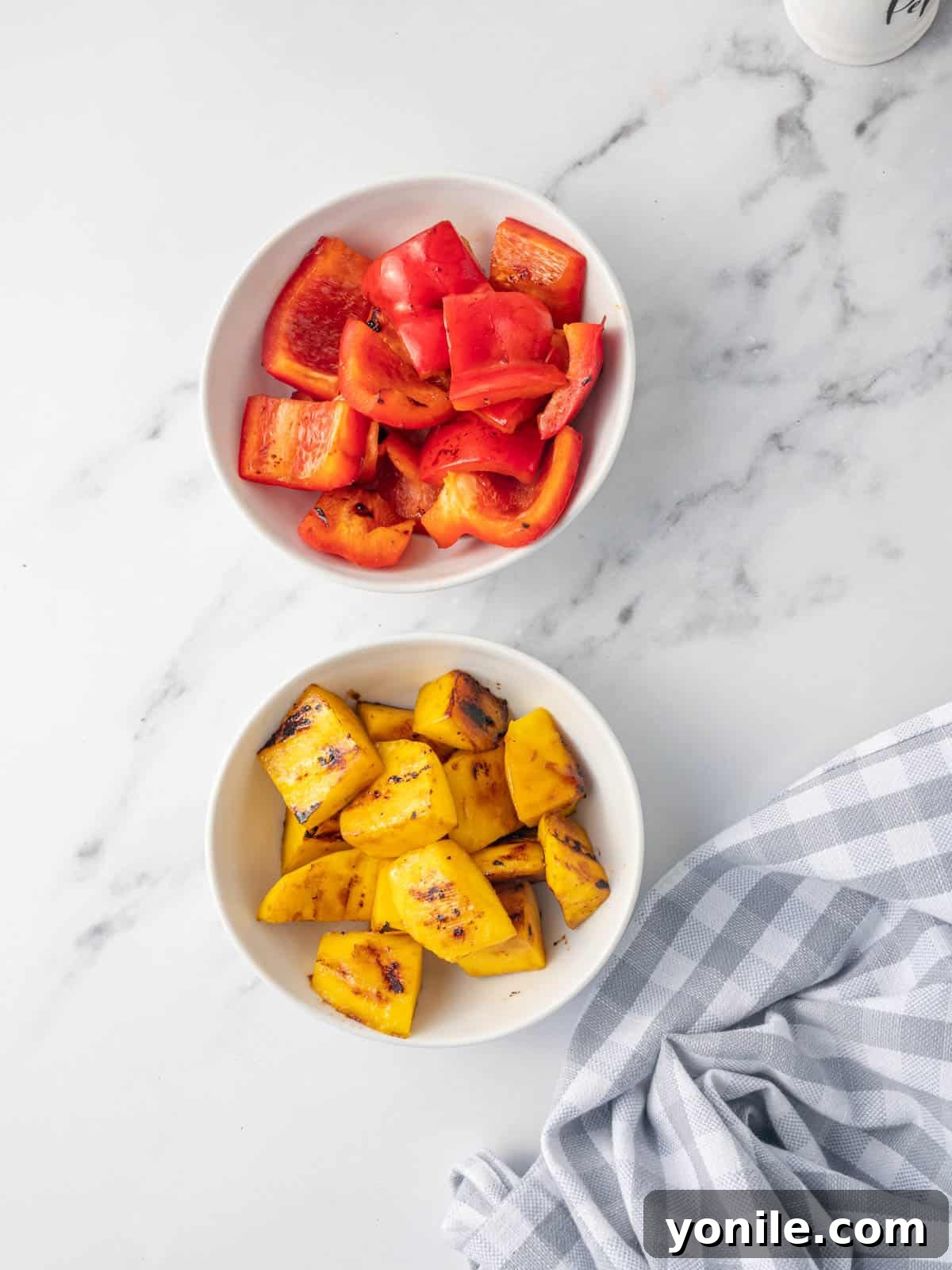Bowls filled with freshly sautéed mango chunks and vibrant red bell pepper cubes, ready for assembly.