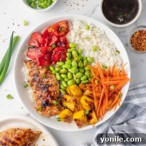 A teriyaki chicken rice bowl with condiments on the side.