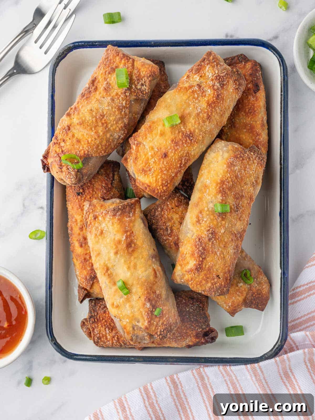 A platter of crispy homemade spring rolls with dipping sauce.