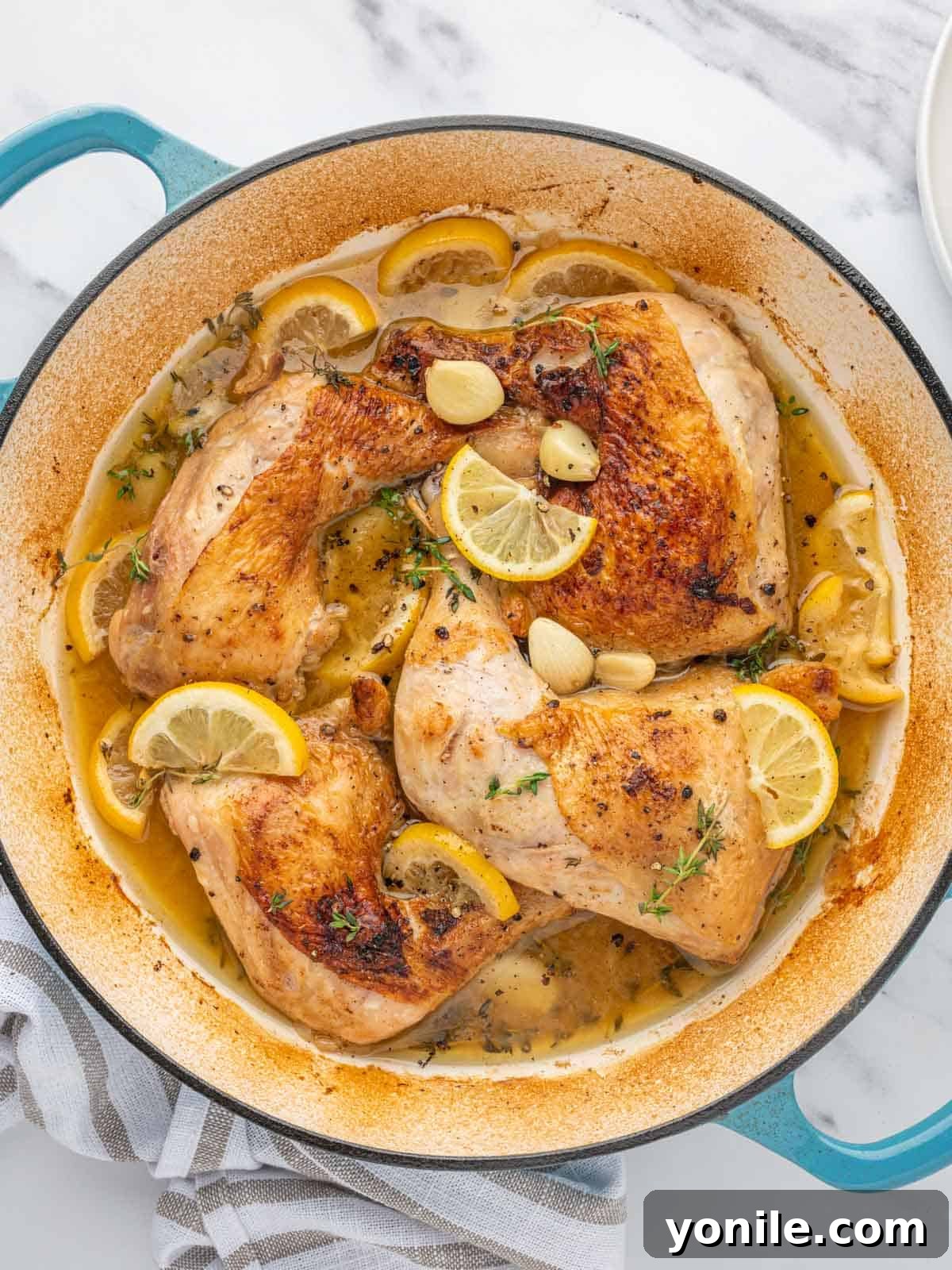 Braised chicken leg quarters with lemon and garlic in a dutch oven.