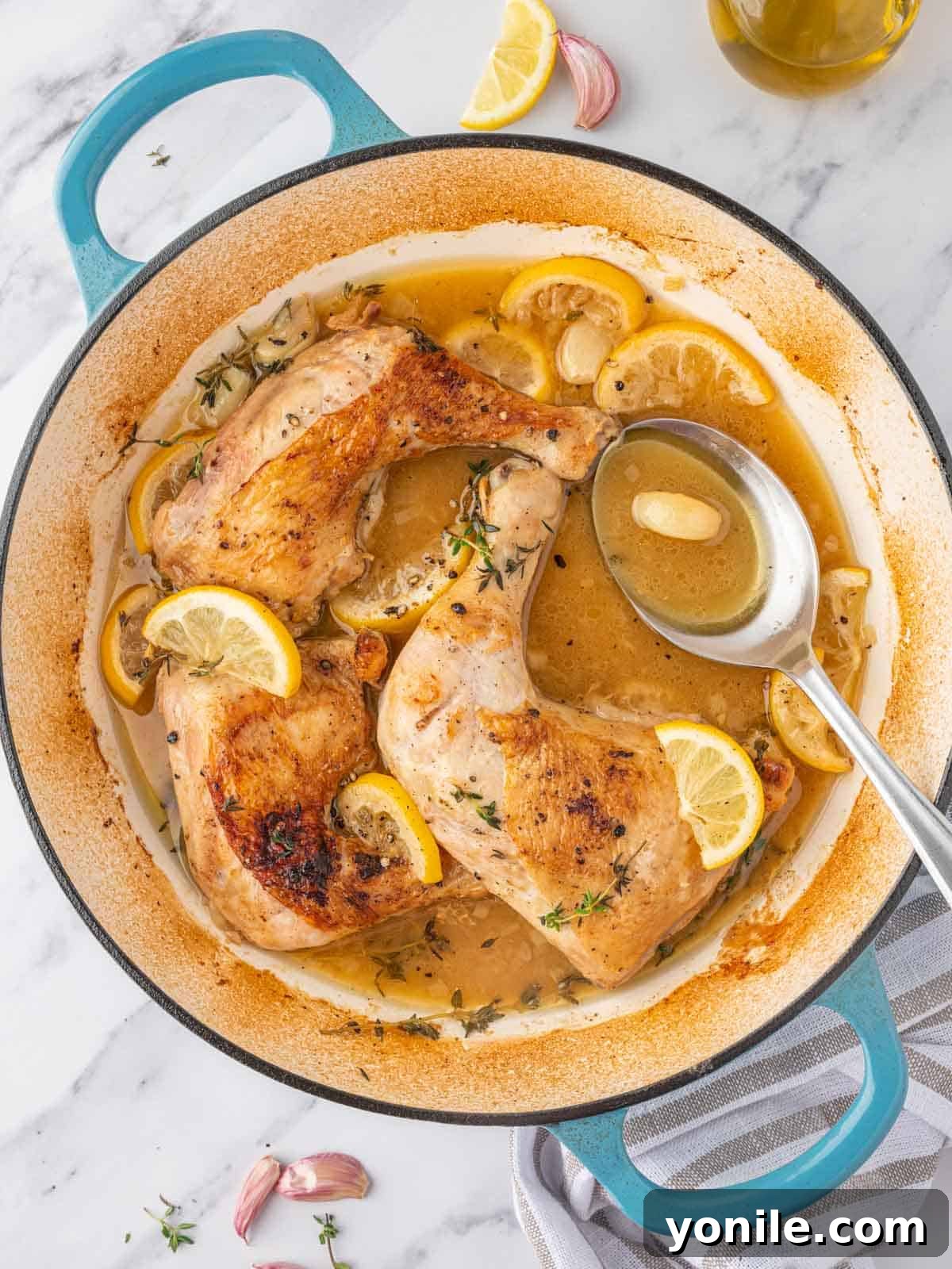 A spoon bastes braised chicken quarters.