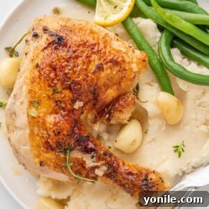Braised chicken quarter on a plate with mashed potatoes.