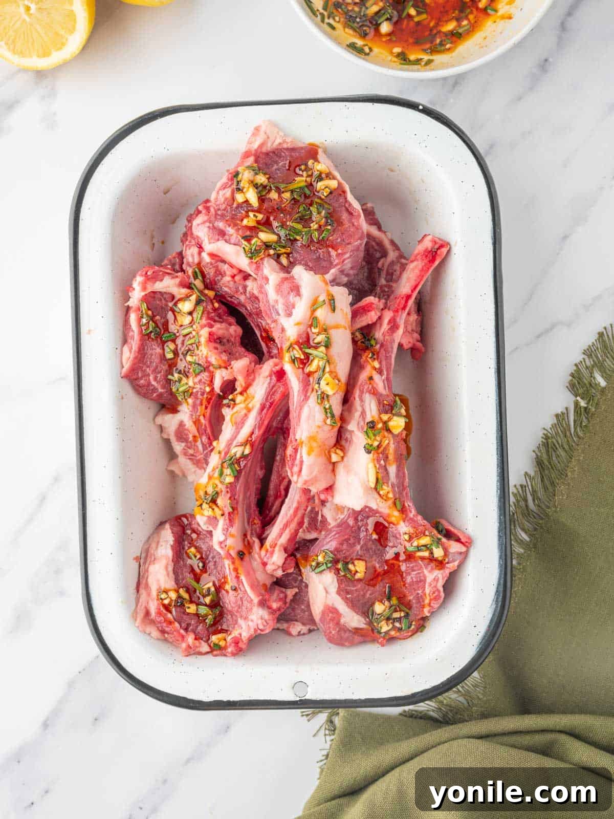 Raw lamb chops coated in the Mediterranean marinade, resting in a dish.