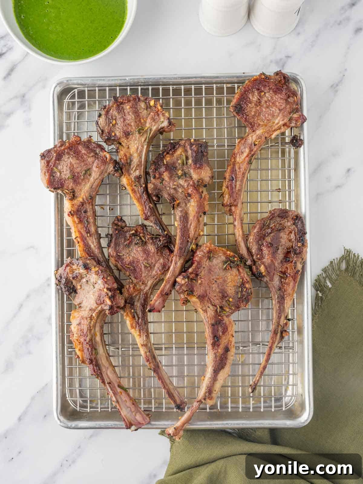 Perfectly grilled lamb chops resting on a serving platter, showing beautiful grill marks.