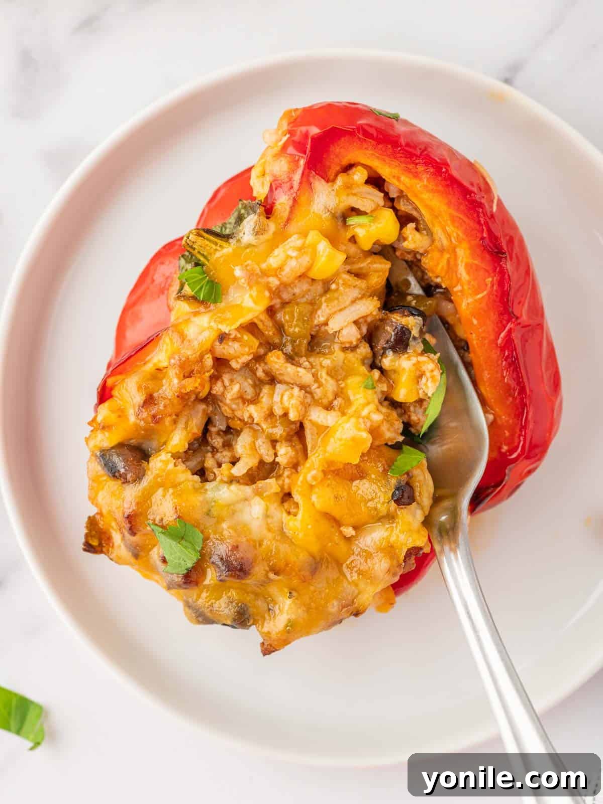 A fork scoops filling out of a stuffed pepper.