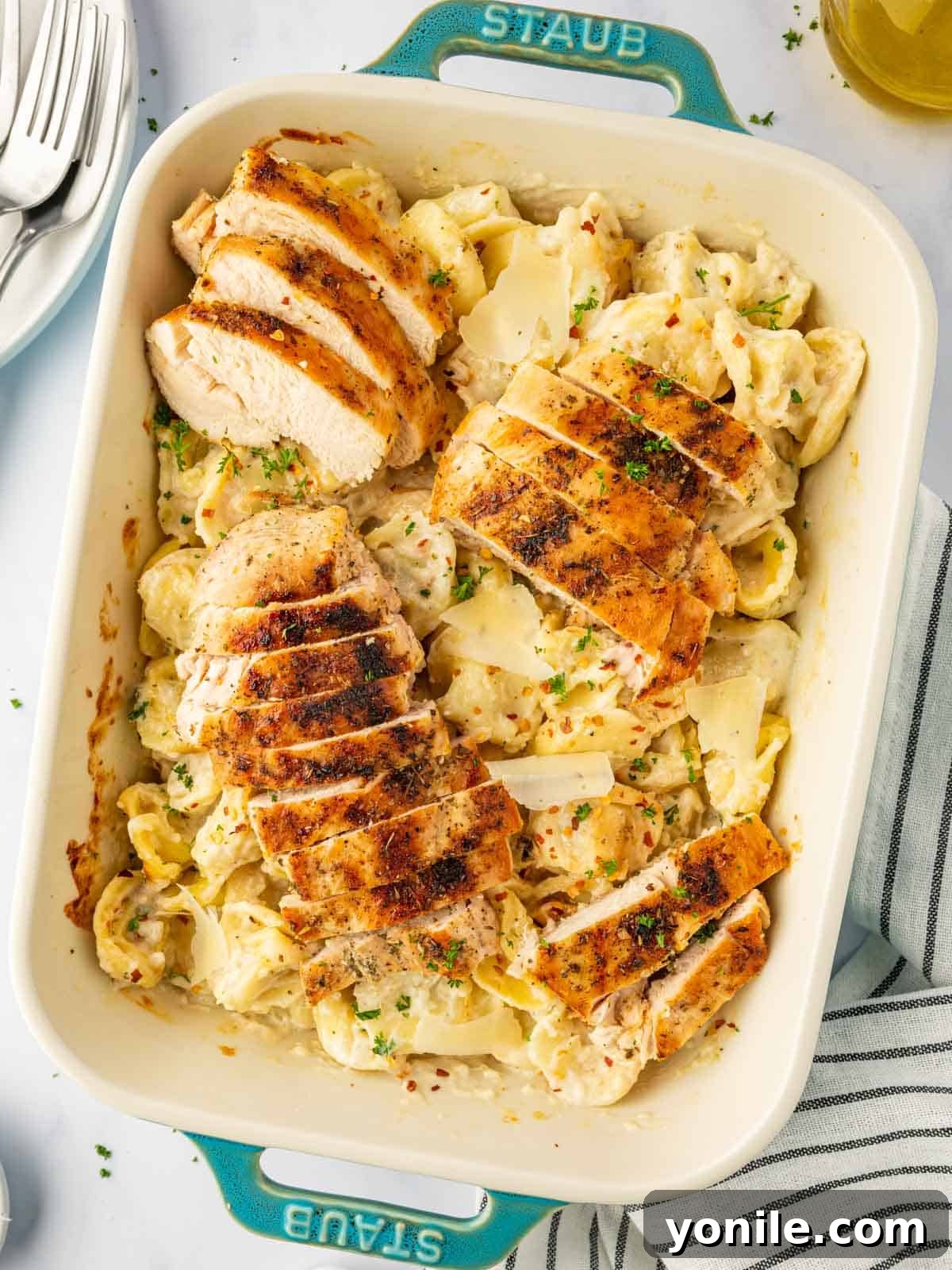 Velvety Chicken Tortellini Alfredo 2 A baking dish with alfredo tortellini and sliced grilled chicken, ready to serve.