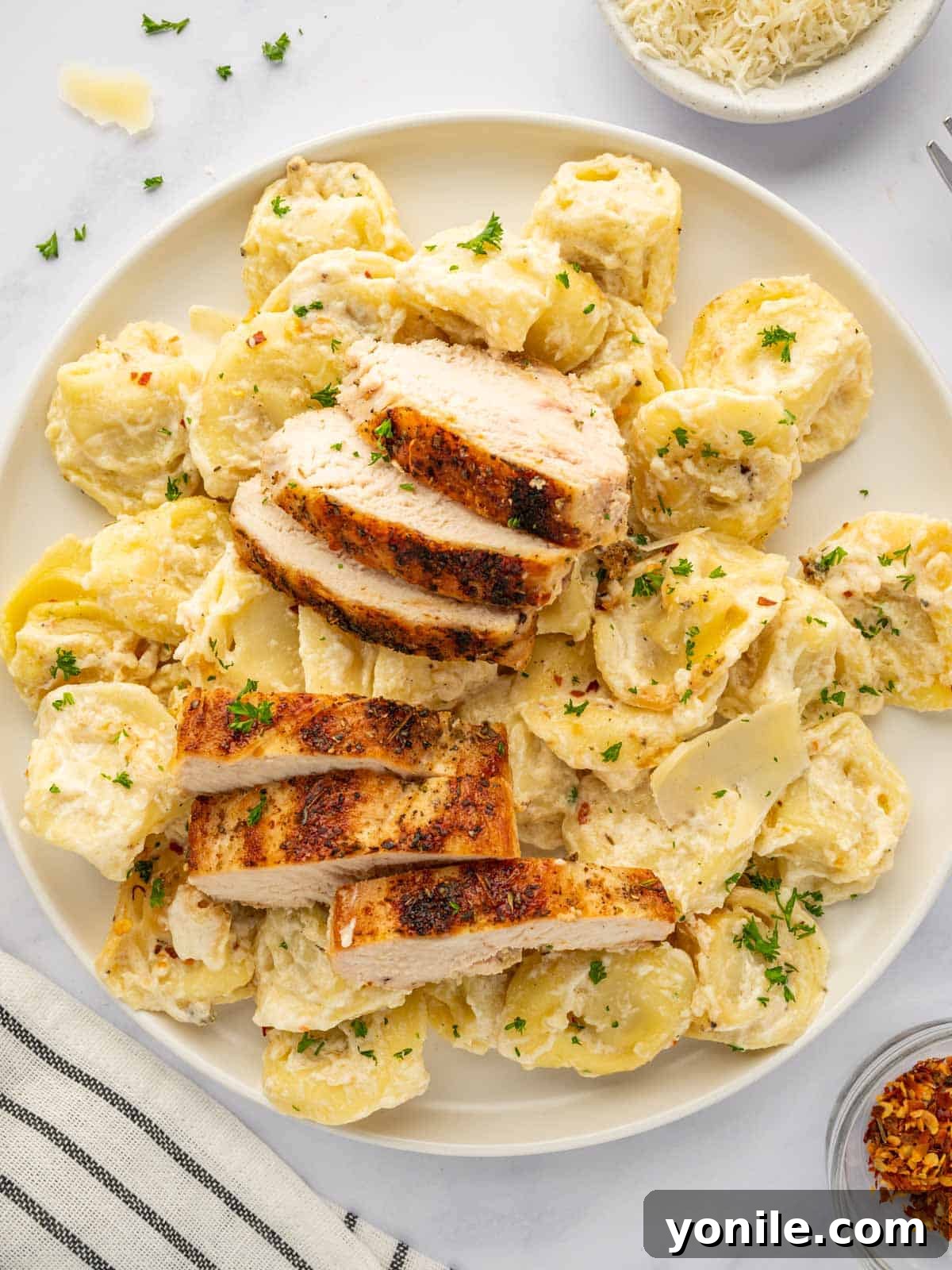 Velvety Chicken Tortellini Alfredo 9 A plate featuring a generous serving of tortellini alfredo with tender slices of grilled chicken.