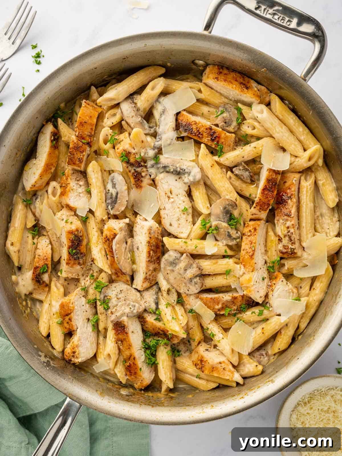 A skillet is filled with Creamy Garlic Parmesan Chicken and Mushroom pasta, ready to serve.