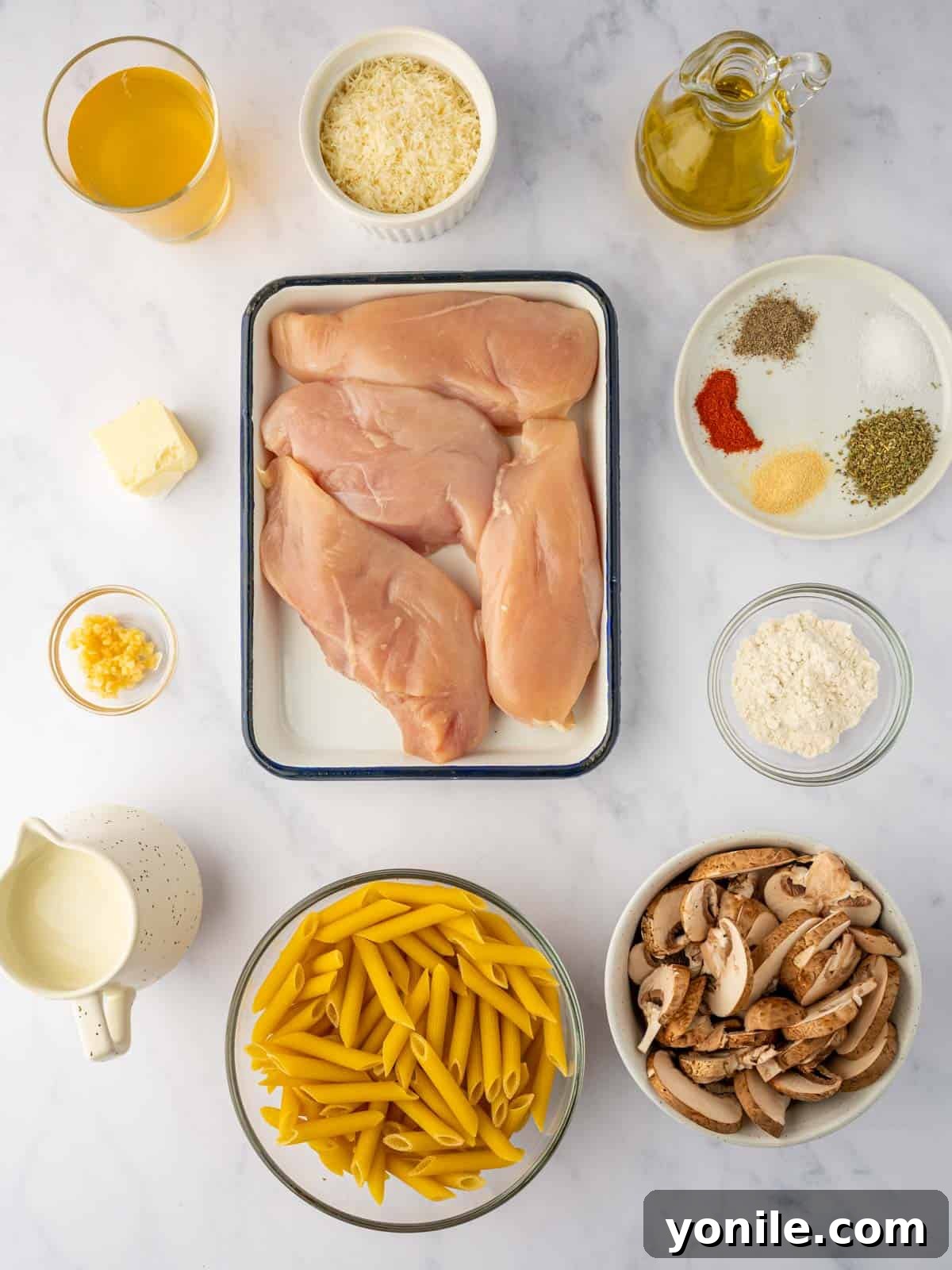 Ingredients needed for creamy chicken parmesan garlic pasta laid out on a counter.