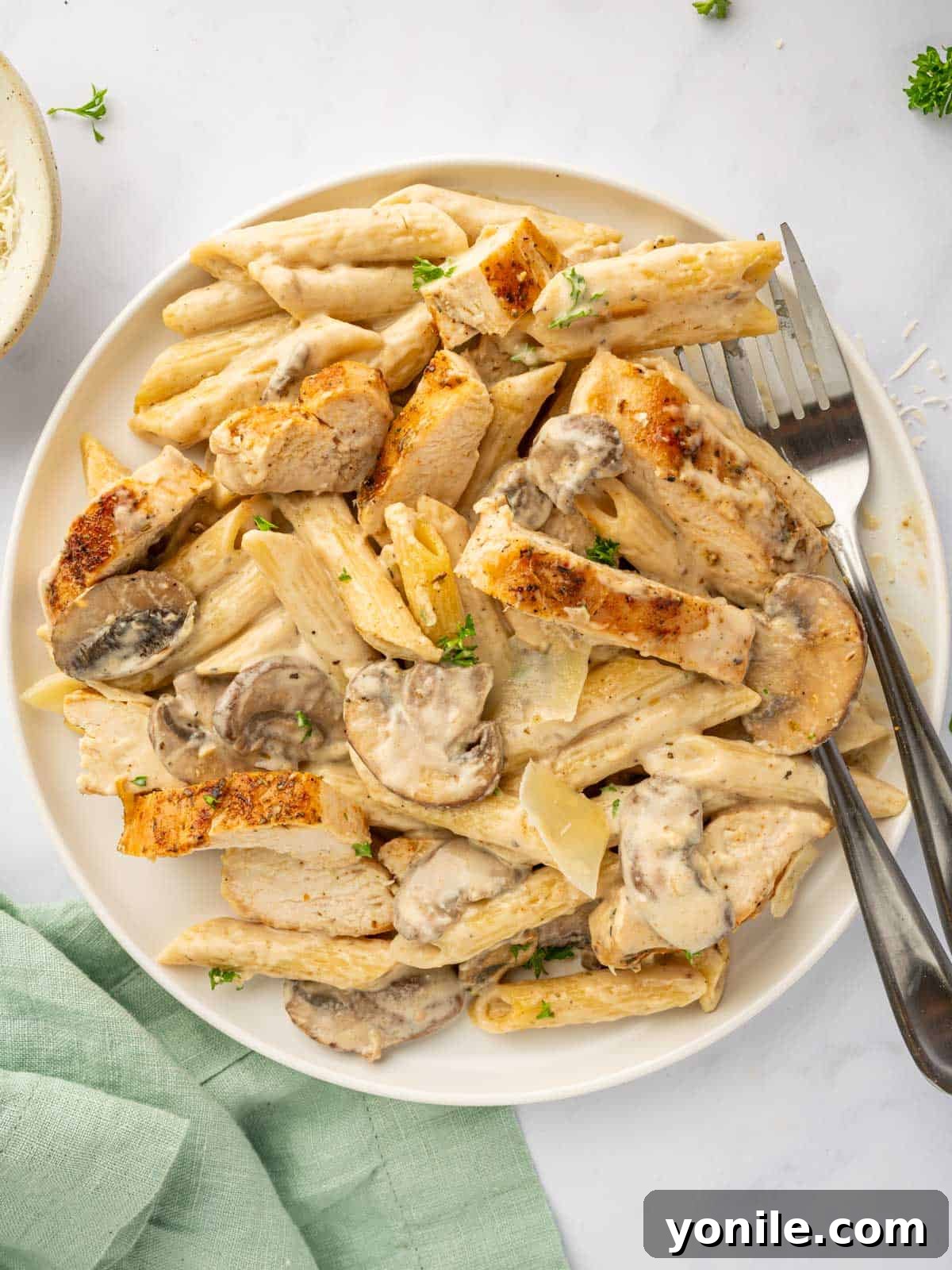 A fork rests on a plate of creamy chicken parmesan garlic pasta, ready to be enjoyed.