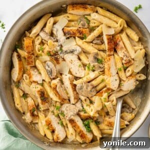 A spoon scoops a portion of garlic parm chicken pasta.