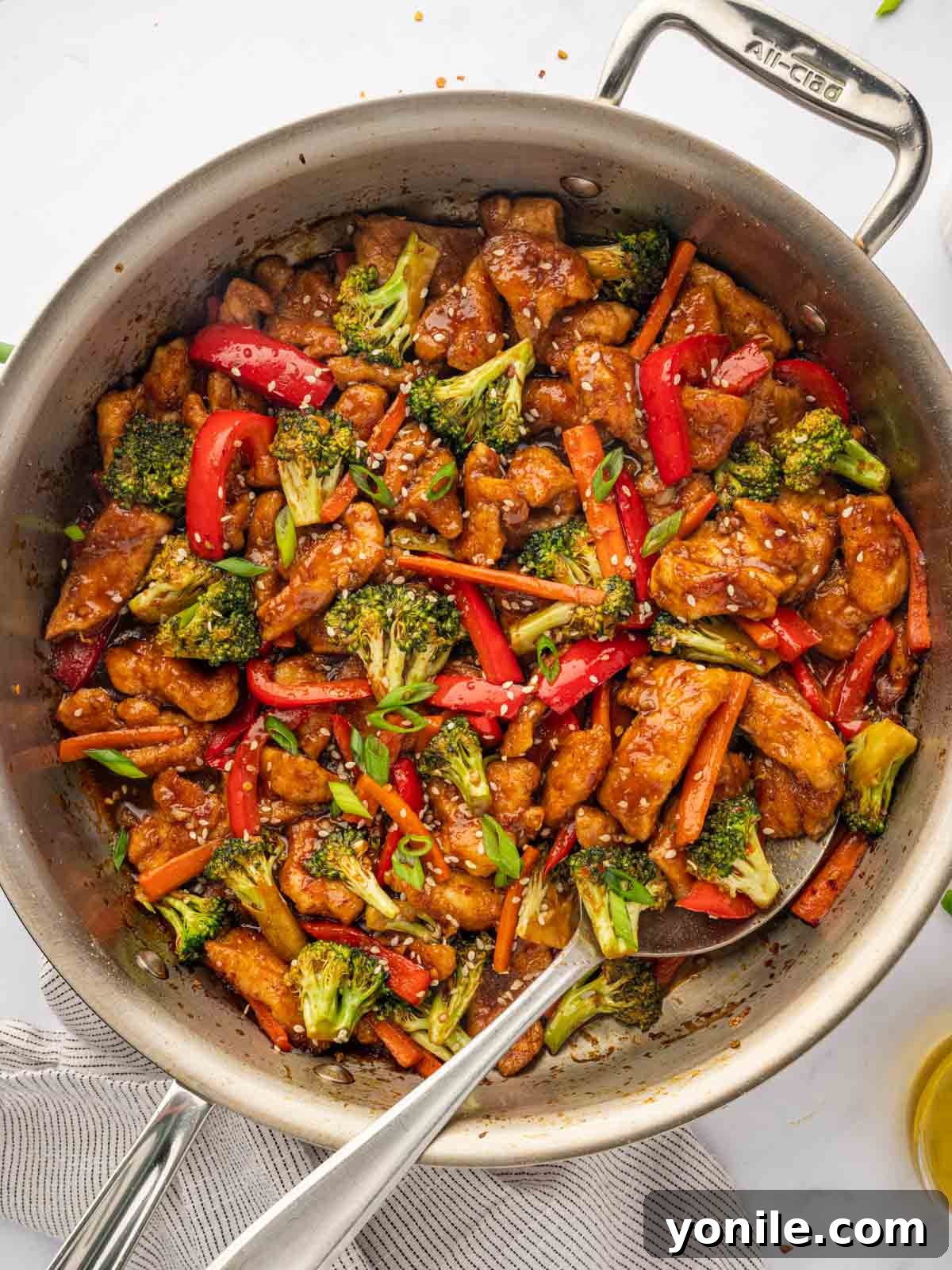 Fiery Hunan Chicken 2 Hunan chicken recipe in a skillet with a spoon, ready to be served over rice.