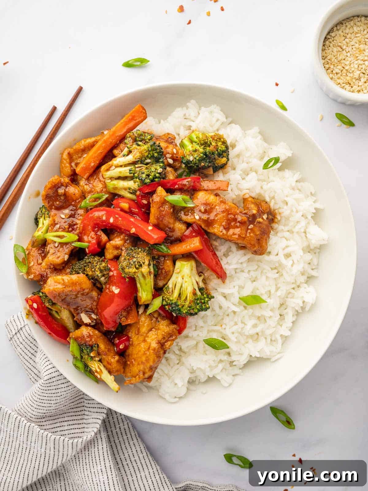 Fiery Hunan Chicken 8 Chinese Hunan chicken served over rice with chopsticks, inviting a delicious meal experience.