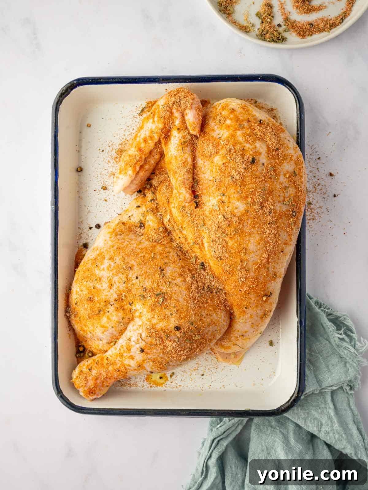 A half chicken is seasoned with herbs and spices.