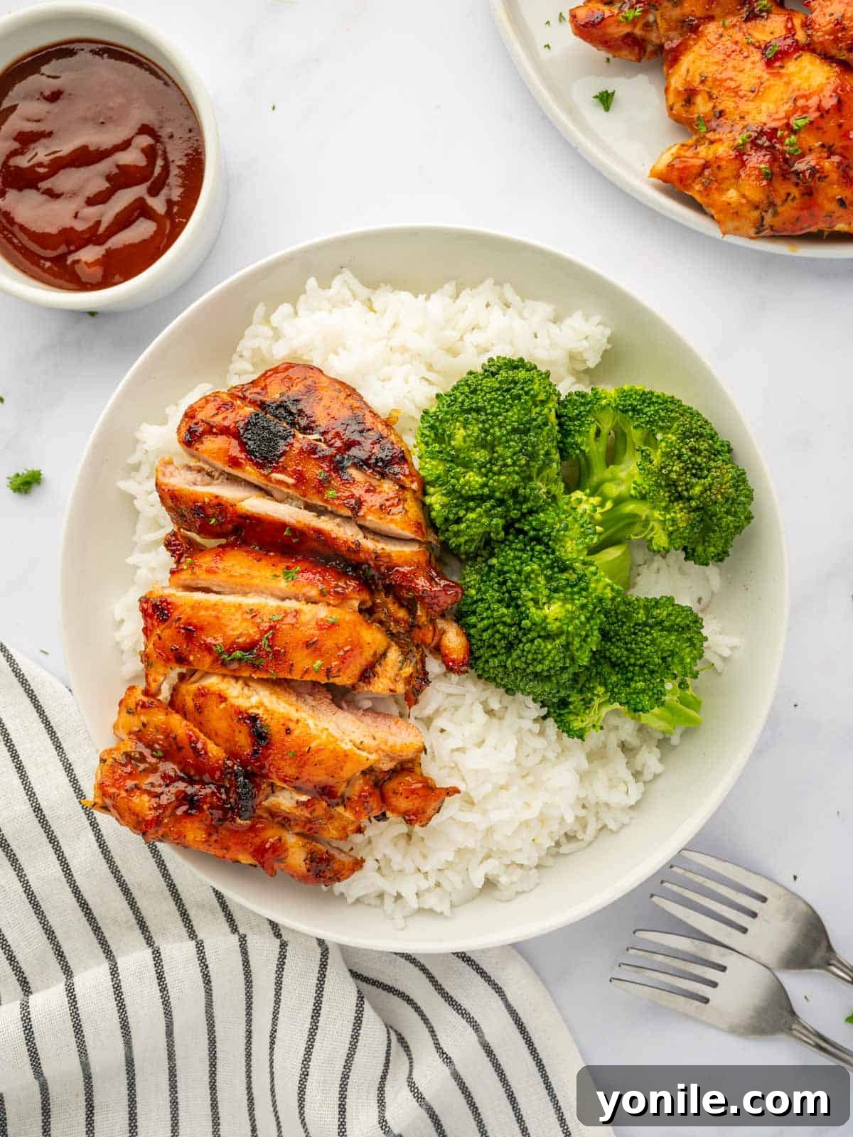 Succulent Oven Baked BBQ Chicken Thighs served with fresh broccoli and fluffy rice, ready to be enjoyed.