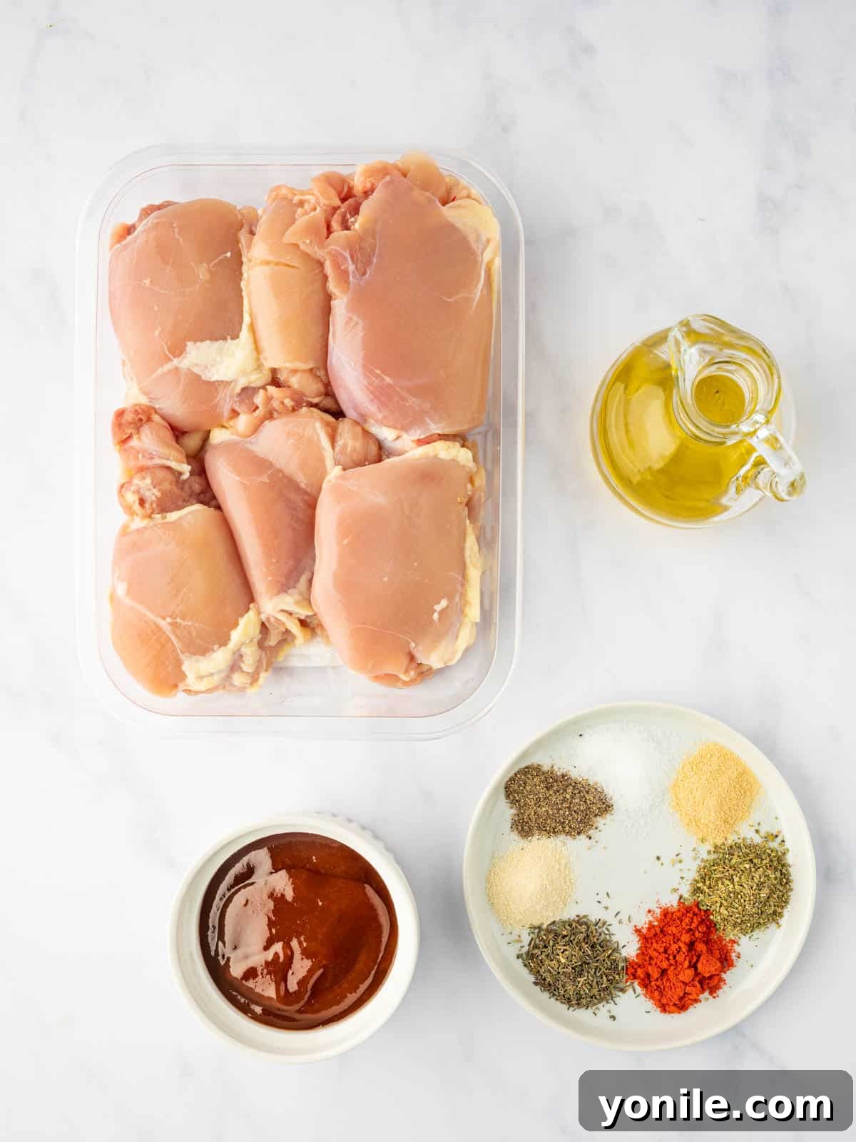 A vibrant flat lay showcasing all the fresh and dried ingredients needed to prepare delicious oven-baked BBQ chicken thighs.