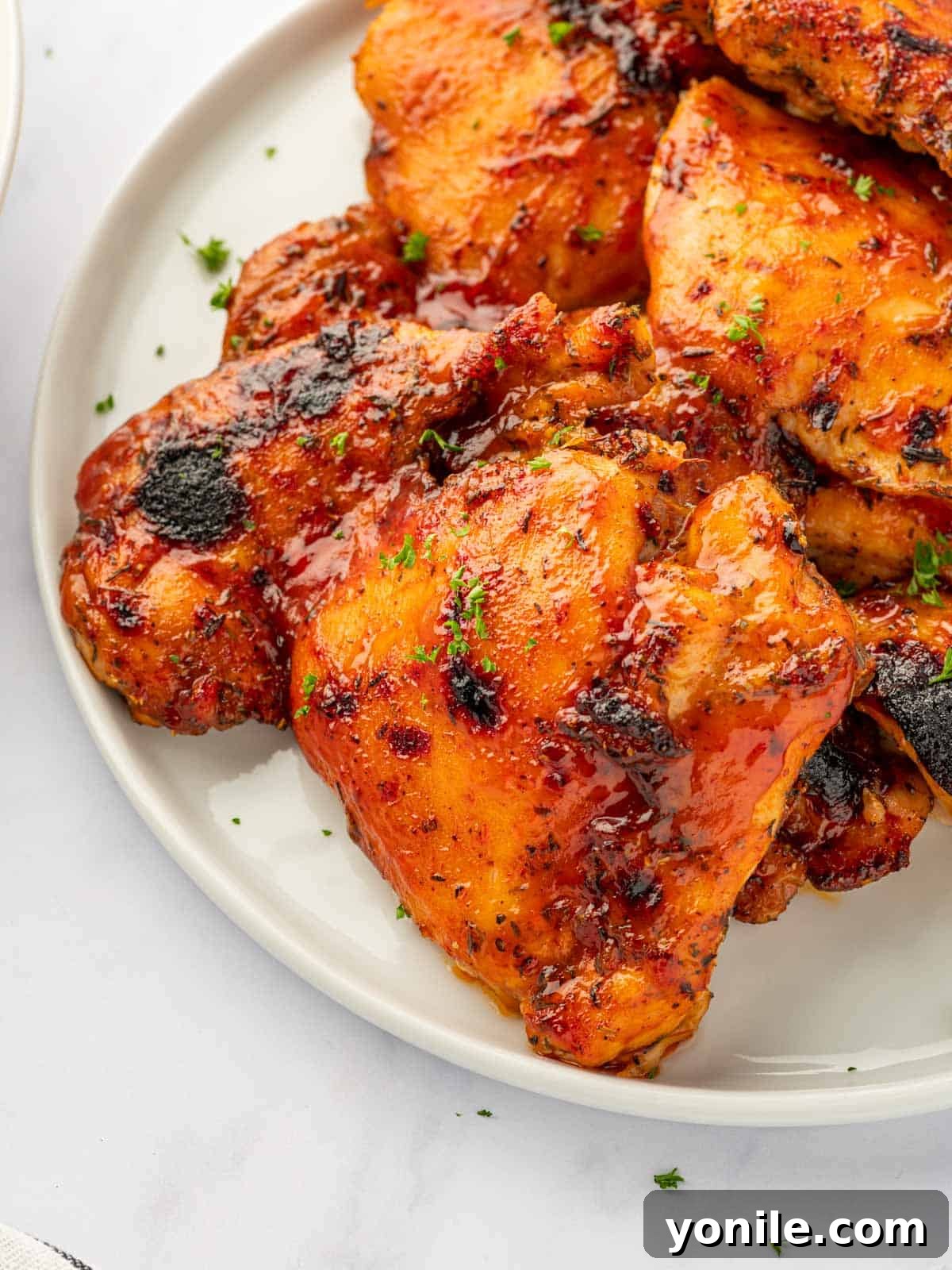 A delectable close-up of baked barbecue chicken thighs artfully arranged on a plate, highlighting their succulent texture and rich glaze.