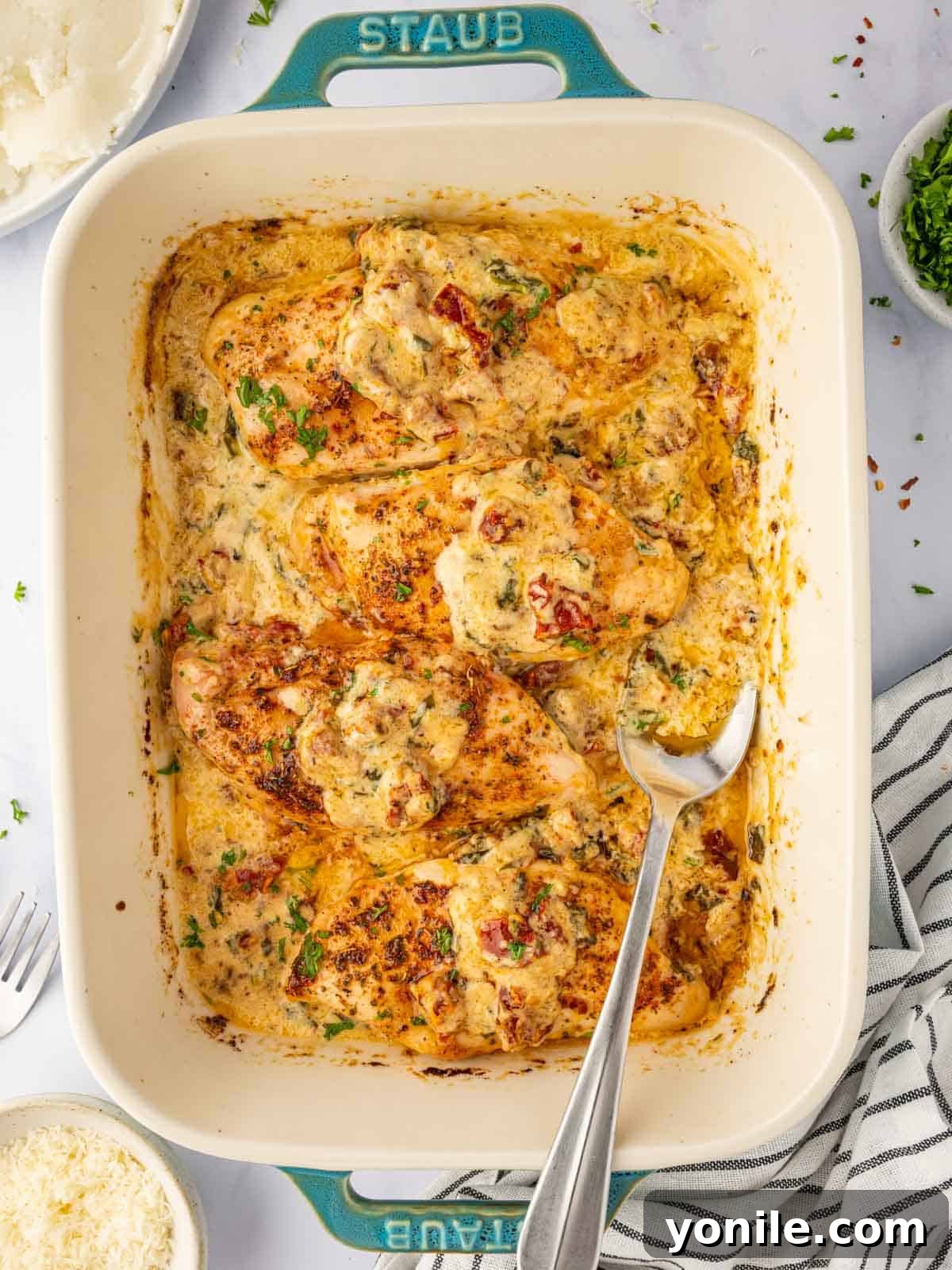 Creamy Tuscan Oven Chicken 6 A spoon scoops tuscan sauce from the casserole dish.