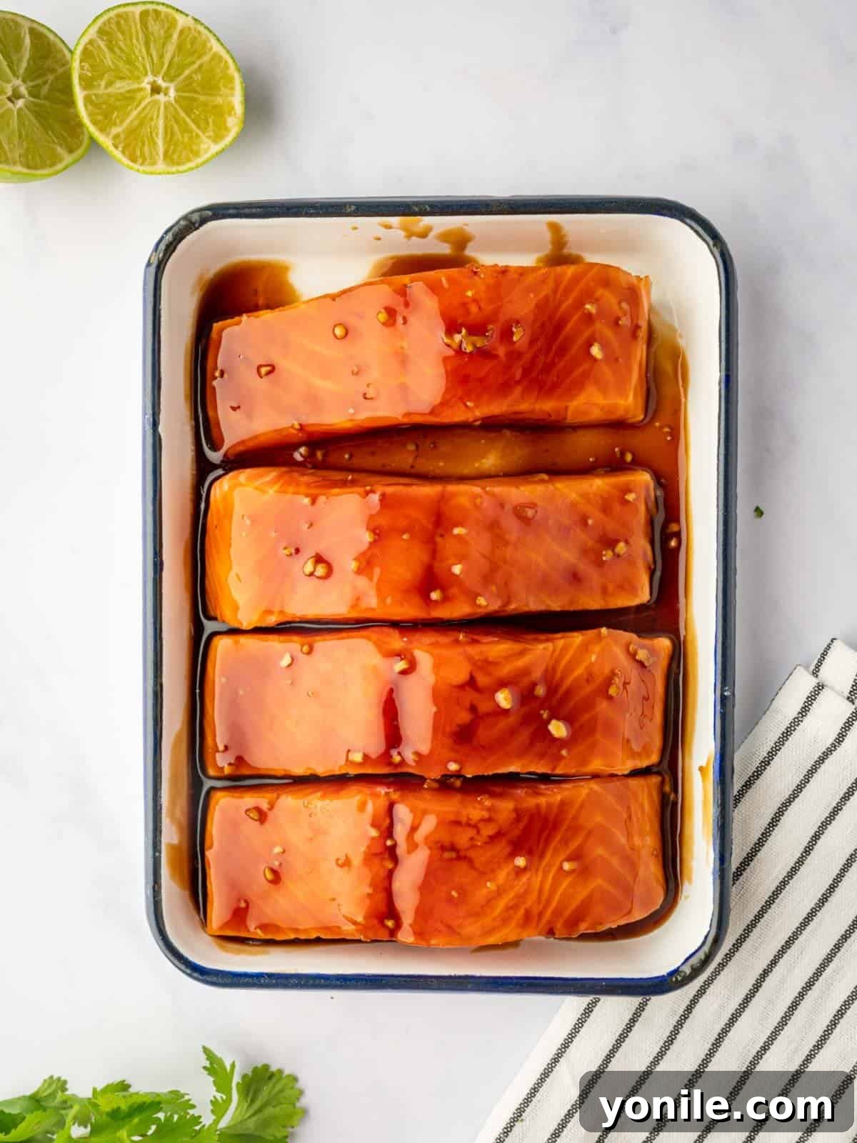 Salmon fillets marinating in teriyaki sauce in a bowl.