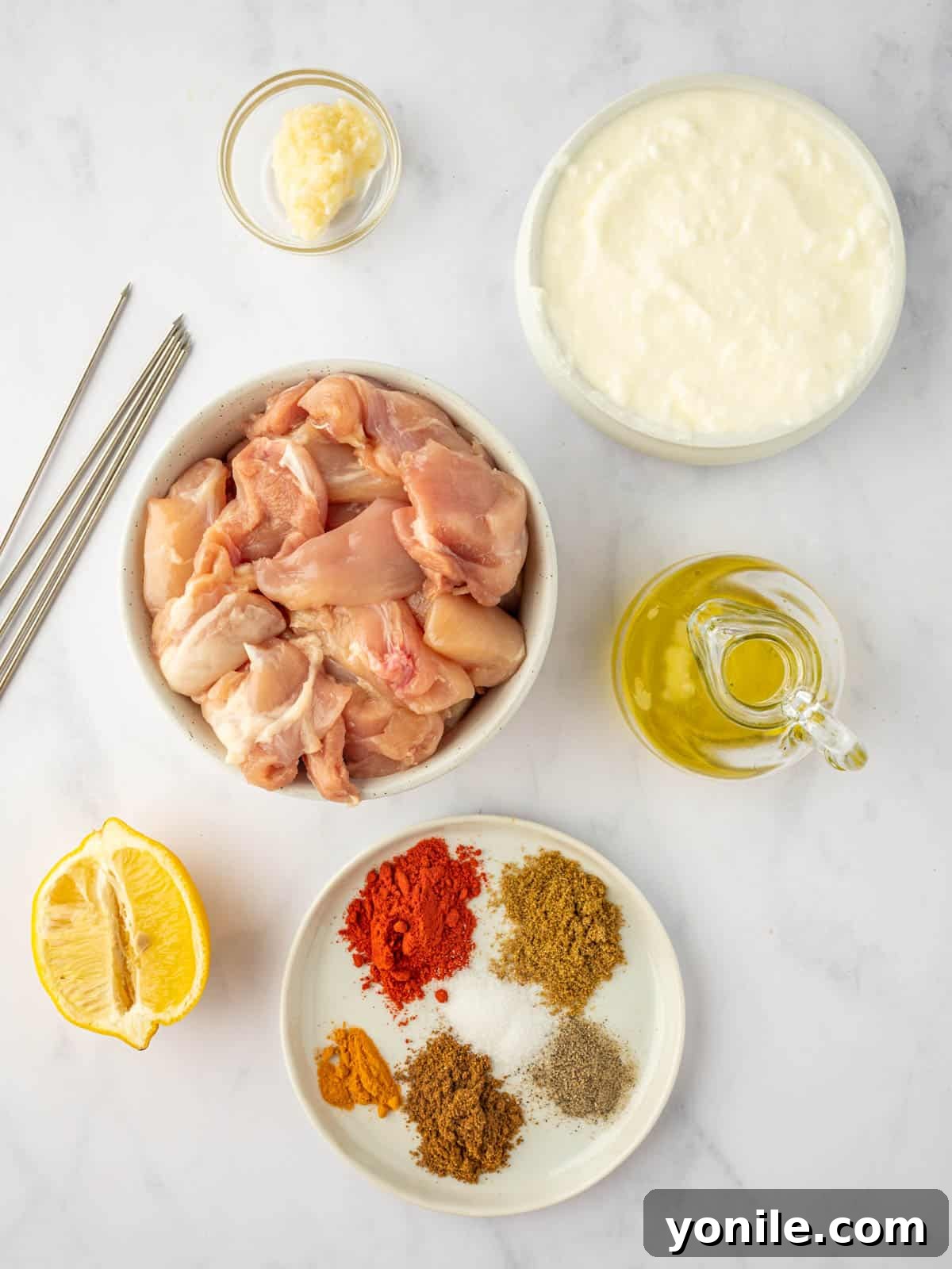 A collection of fresh ingredients laid out for making tandoori chicken kebabs.