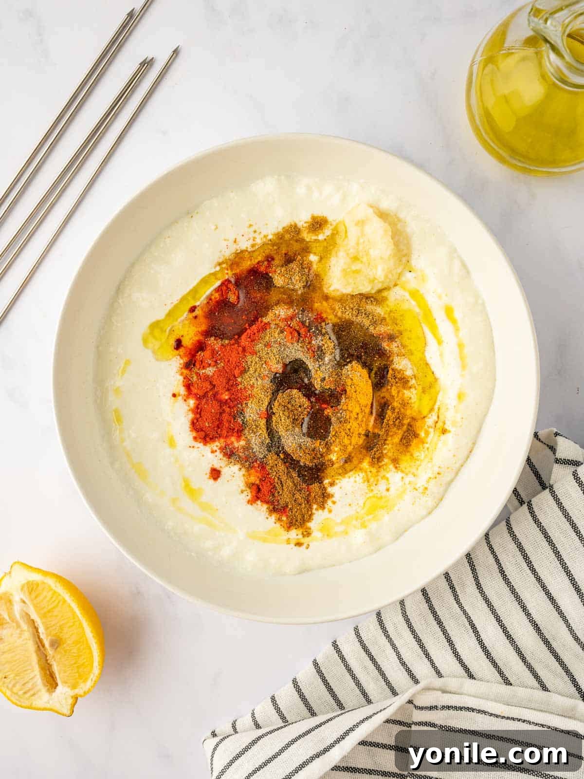 Yogurt and a vibrant mix of Tandoori spices being combined in a bowl for the marinade.