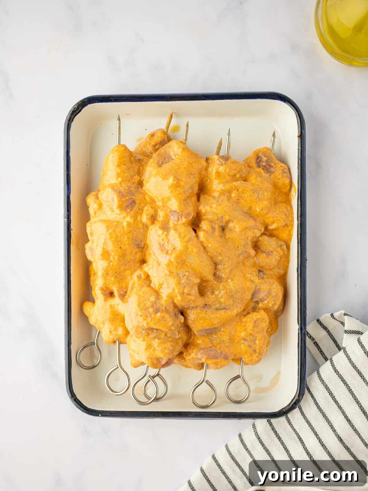Marinated Tandoori chicken pieces carefully threaded onto skewers, ready for grilling.