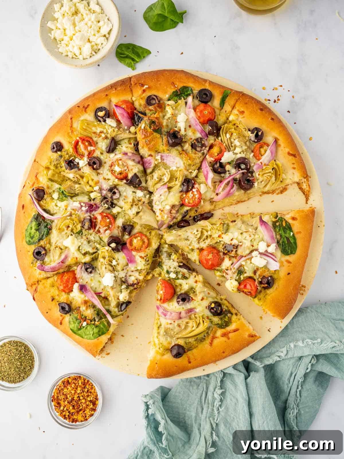Homemade Mediterranean Pizza Feast 2 Perfectly sliced homemade Mediterranean pizza with feta, artichokes, and olives, resting on a rustic pizza stone.