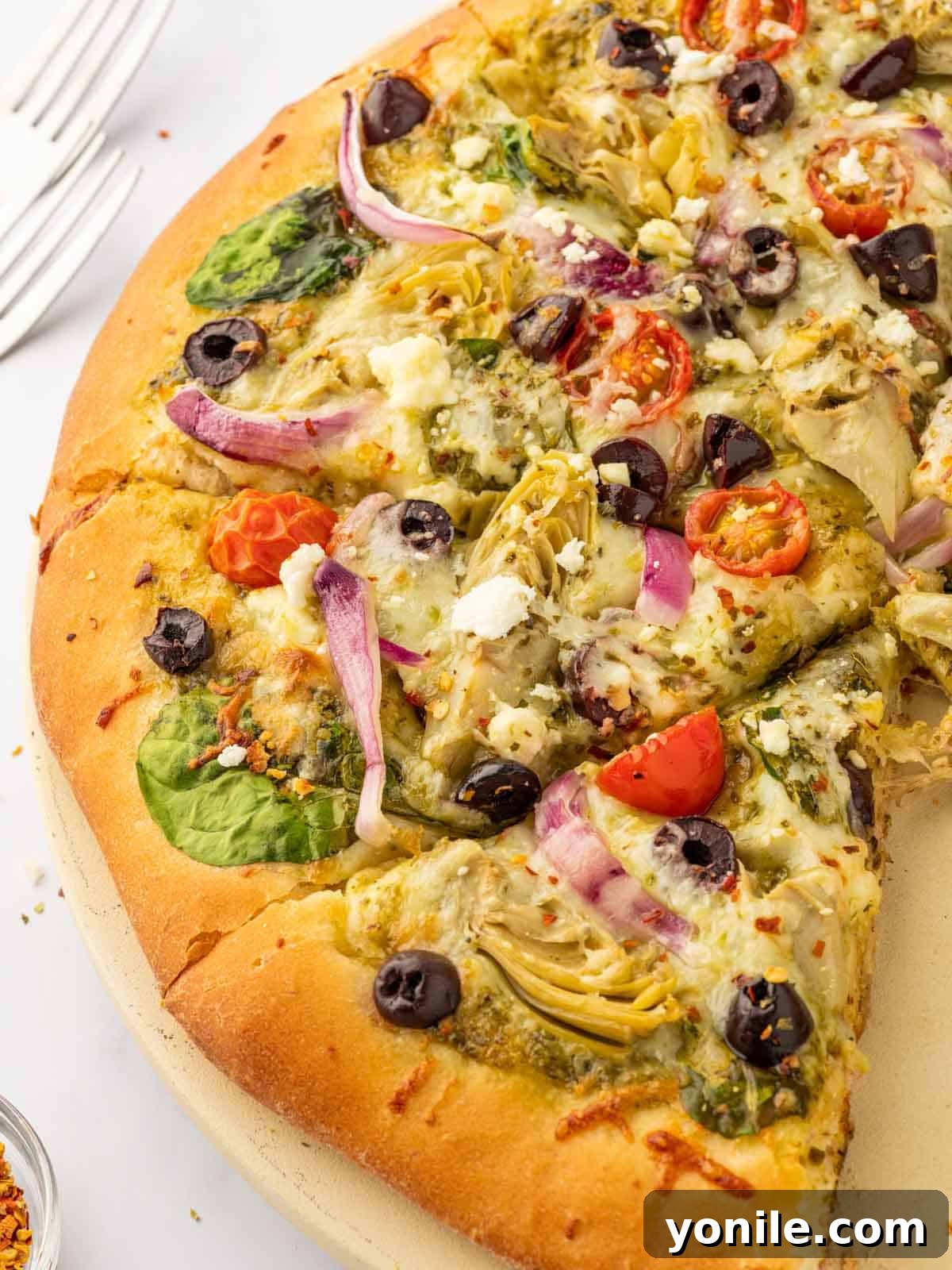 Homemade Mediterranean Pizza Feast 9 Close-up view of a Mediterranean pizza featuring crumbled feta, vibrant artichoke hearts, and rich Kalamata olives on a golden crust.