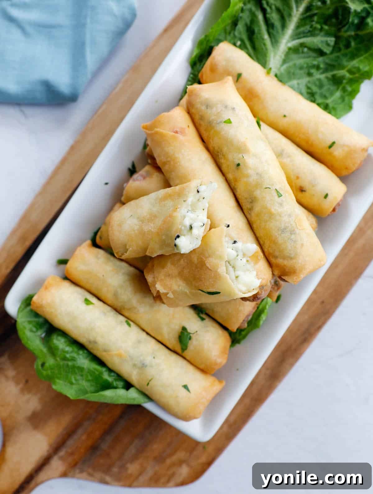 Crispy Cheese Rolls 8 An appetizing close-up of crispy, golden-brown Lebanese Cheese Rolls, freshly fried and artfully arranged on a wooden board, highlighting their perfect texture and readiness to be devoured.