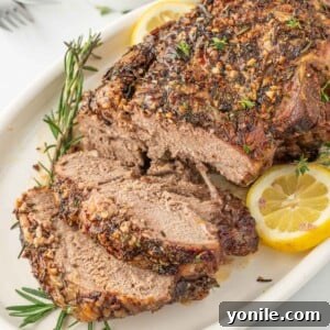 Leg of lamb with slices cut garnished with lemon and rosemary.