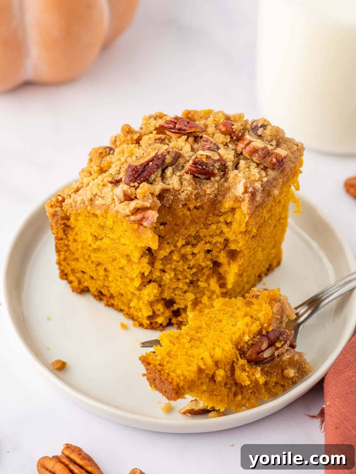 A fork breaking off a piece of pumpkin pecan coffee cake, showing its moist texture.