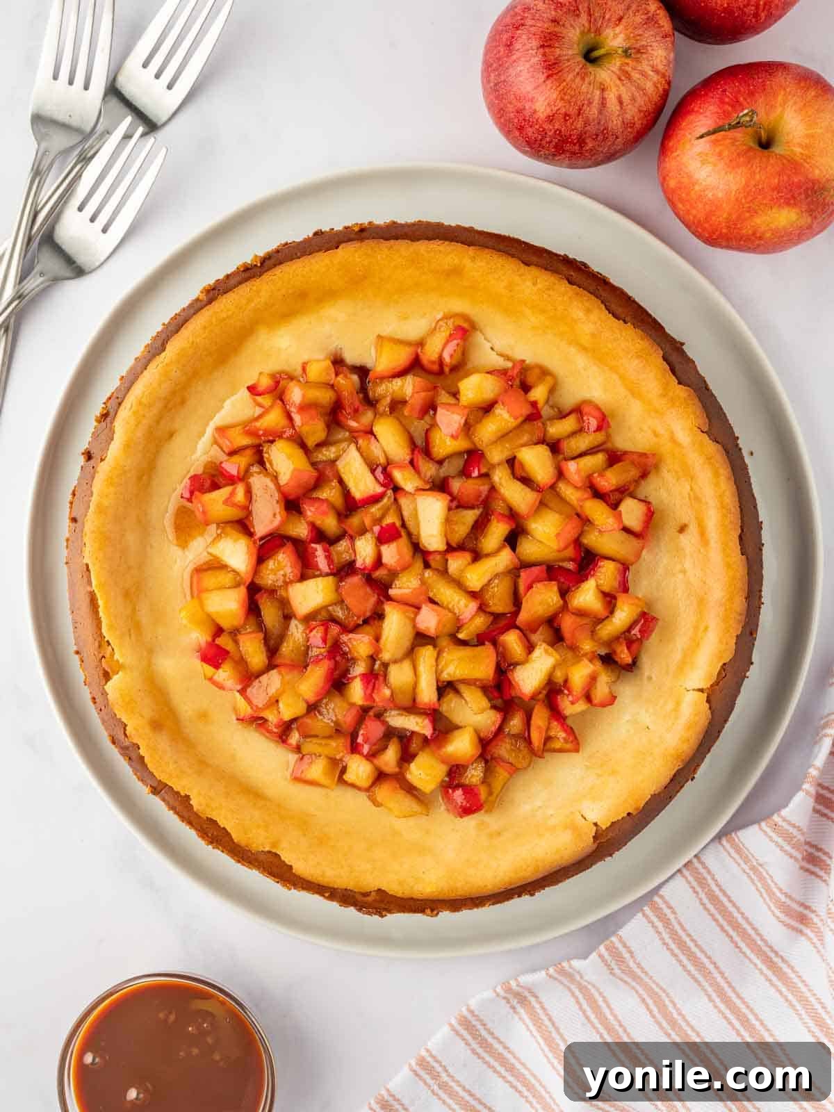 A beautifully baked Cinnamon Apple Cheesecake on a platter, ready to be served, showcasing its golden-brown topping and creamy texture.