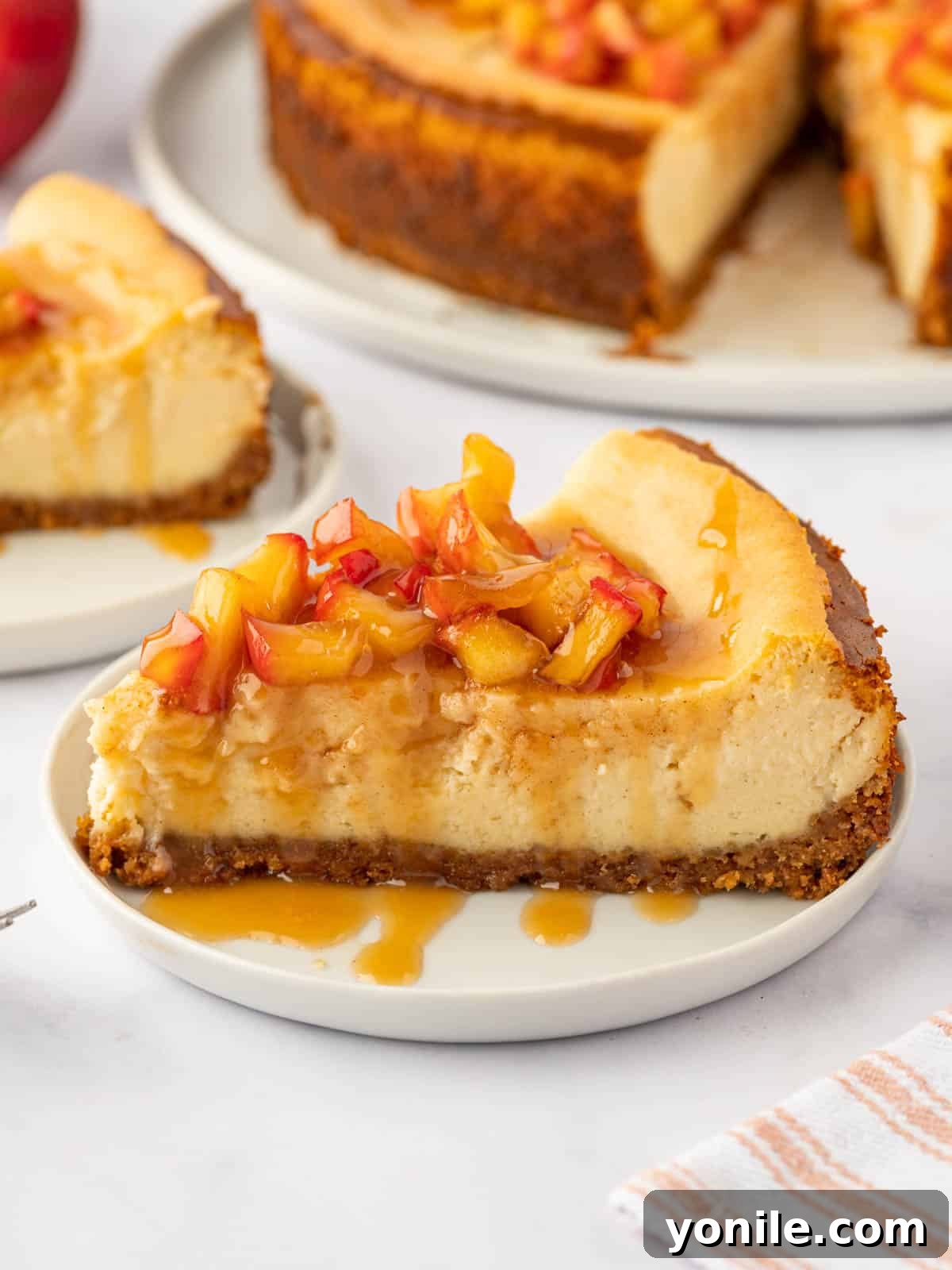 A perfectly sliced piece of creamy cinnamon apple cheesecake, showcasing the rich apple topping and crisp crust on a plate.