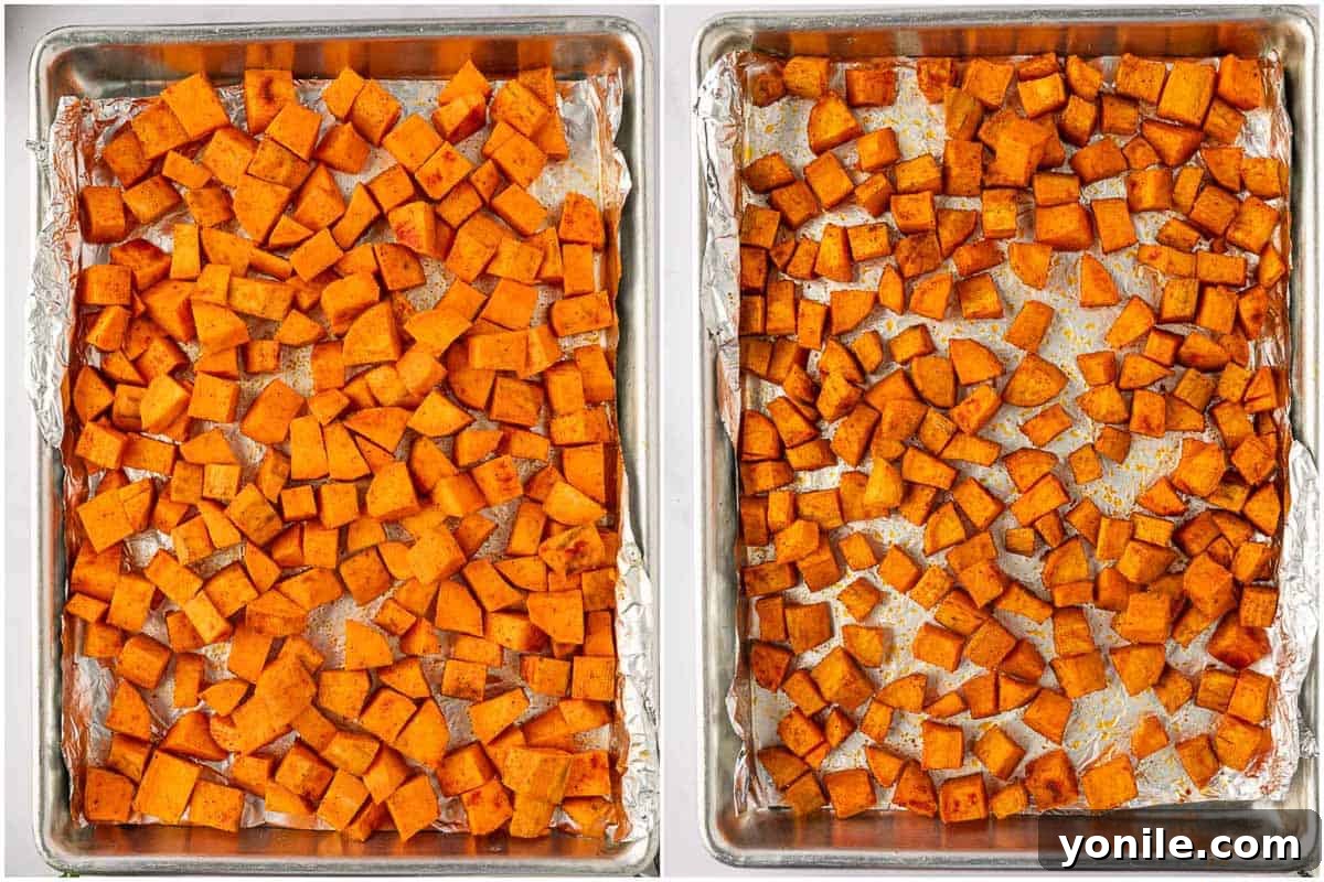 Seasoned sweet potato cubes spread evenly on a parchment-lined baking tray, ready for roasting.