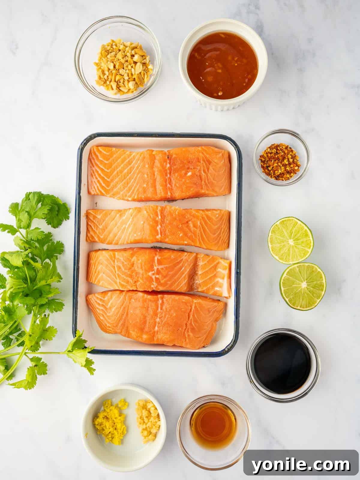 Thai Chili-Lime Baked Salmon 3 All the fresh ingredients meticulously laid out for baking Thai salmon, including vibrant salmon fillets, an assortment of sauces, zesty lime, fresh ginger, aromatic garlic, and garnishes.