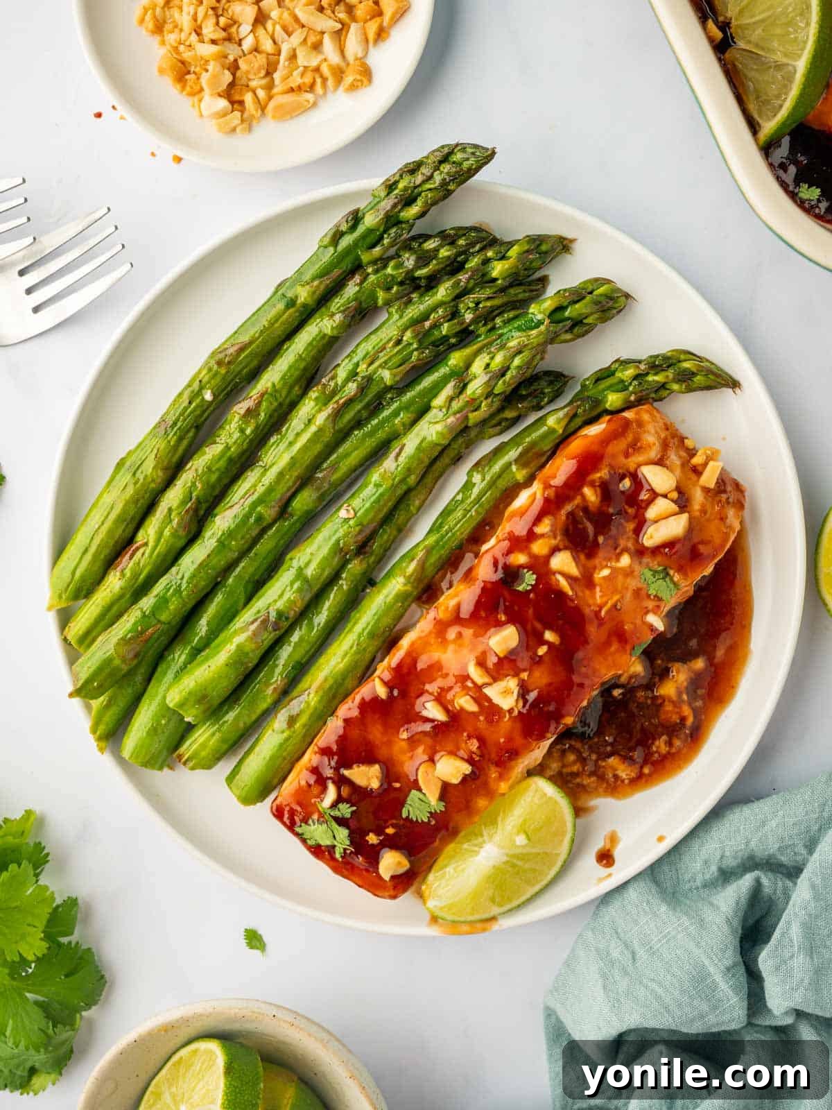 Thai Chili-Lime Baked Salmon 9 Plated baked Thai salmon, beautifully garnished with fresh cilantro and crunchy peanuts, accompanied by bright lime wedges and crisp asparagus for a complete meal.