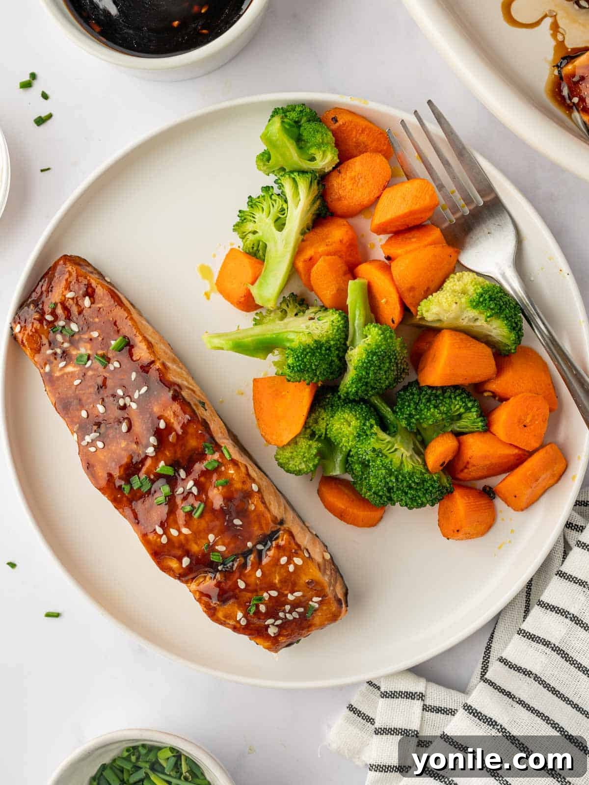 Perfectly cooked Teriyaki Salmon garnished with sesame seeds and chives, ready to be served with fresh vegetables.