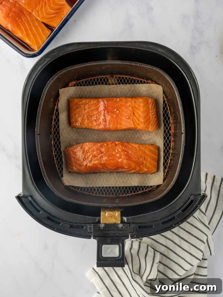 Marinated salmon fillets arranged neatly in an air fryer basket, ready for cooking.