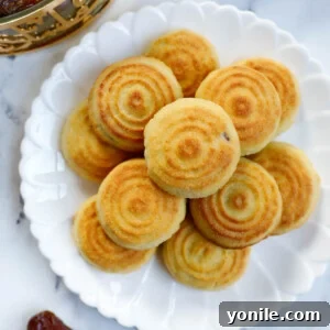 Maamoul Irresistible Date Cookies 17 Date filled maamoul on a white plate, showcasing their intricate designs and golden hue.