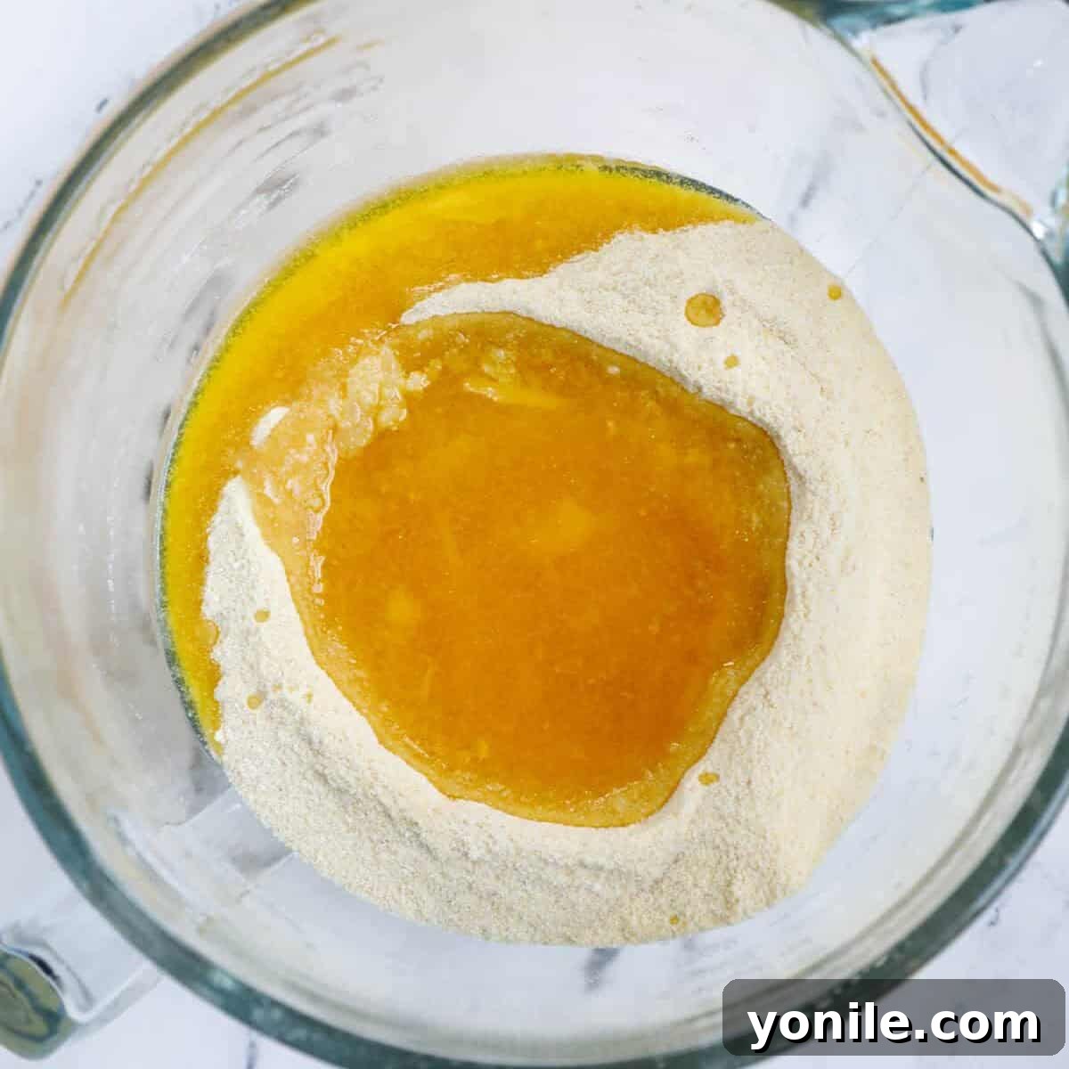 Maamoul Irresistible Date Cookies 4 Warm ghee poured over a dry semolina and flour mixture in a bowl.