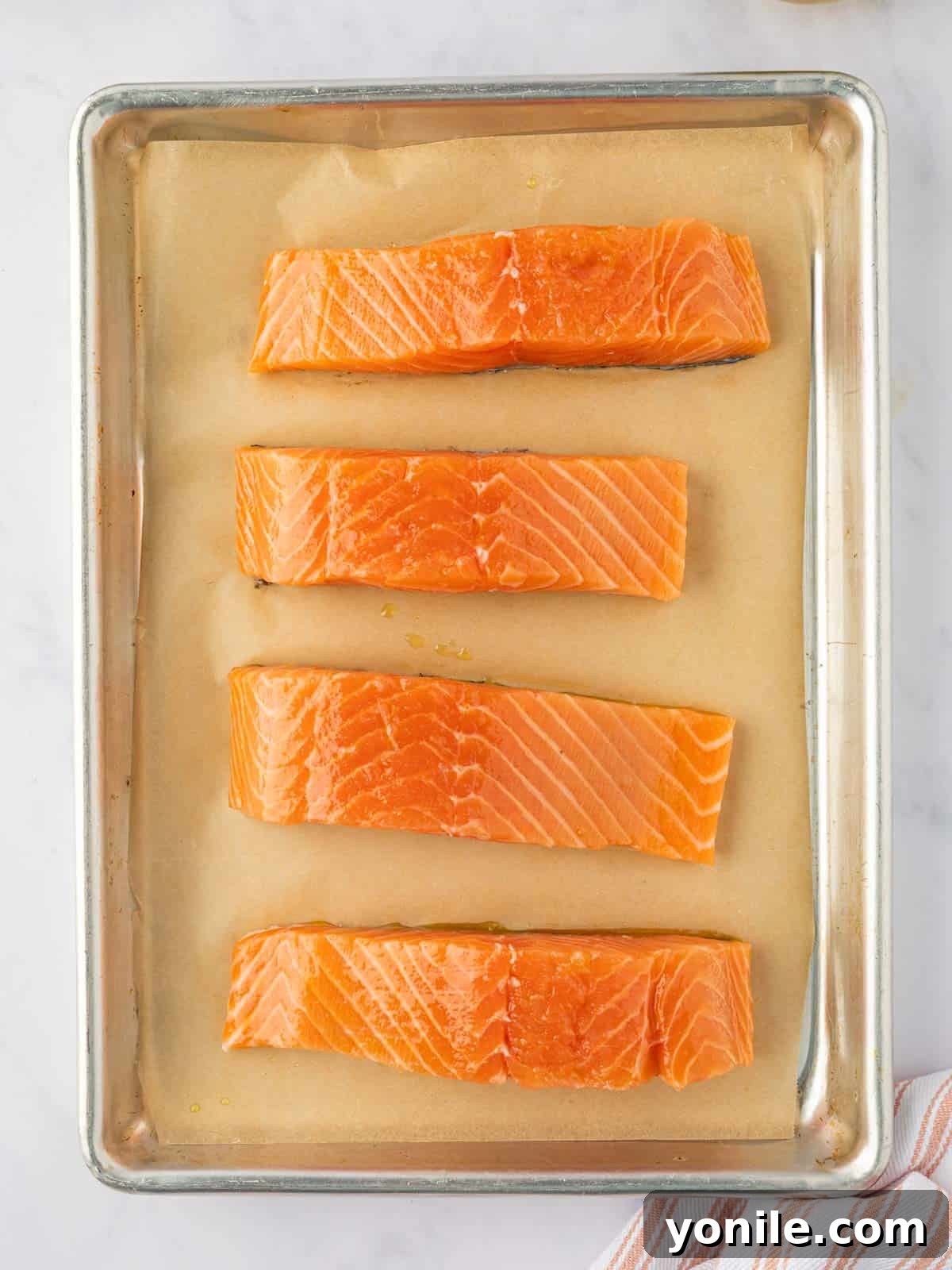 Sweet & Sticky Brown Sugar Salmon 4 Fresh salmon fillets neatly arranged on a baking tray.