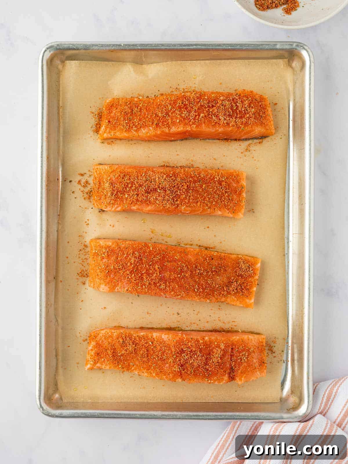Sweet & Sticky Brown Sugar Salmon 5 Salmon fillets generously rubbed with brown sugar seasoning on a baking tray.
