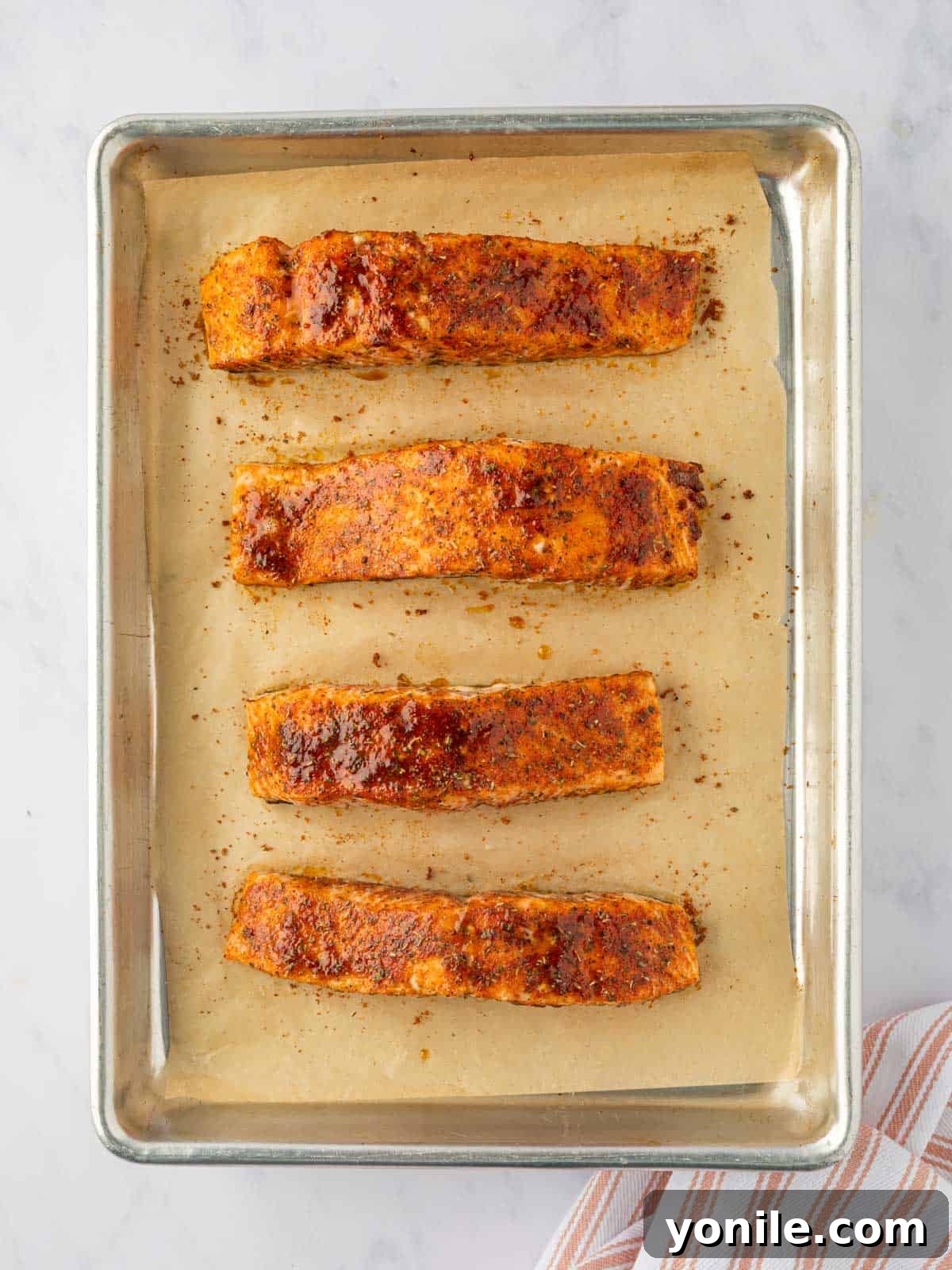 Sweet & Sticky Brown Sugar Salmon 6 Golden-brown baked salmon fillets on a baking tray, fresh from the oven.