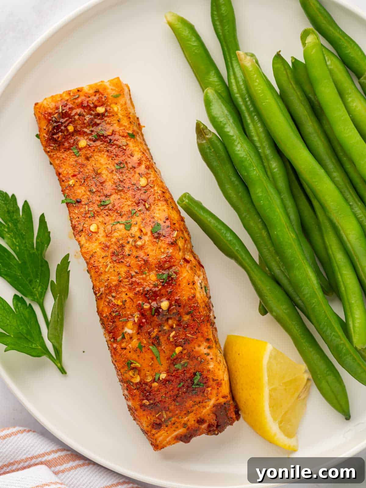 Sweet & Sticky Brown Sugar Salmon 7 Cooked salmon with brown sugar glaze served alongside fresh green beans and a lemon wedge.