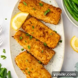 Air fried mahi mahi fish fillet on a platter with lemon slices, showcasing a perfect golden crust.