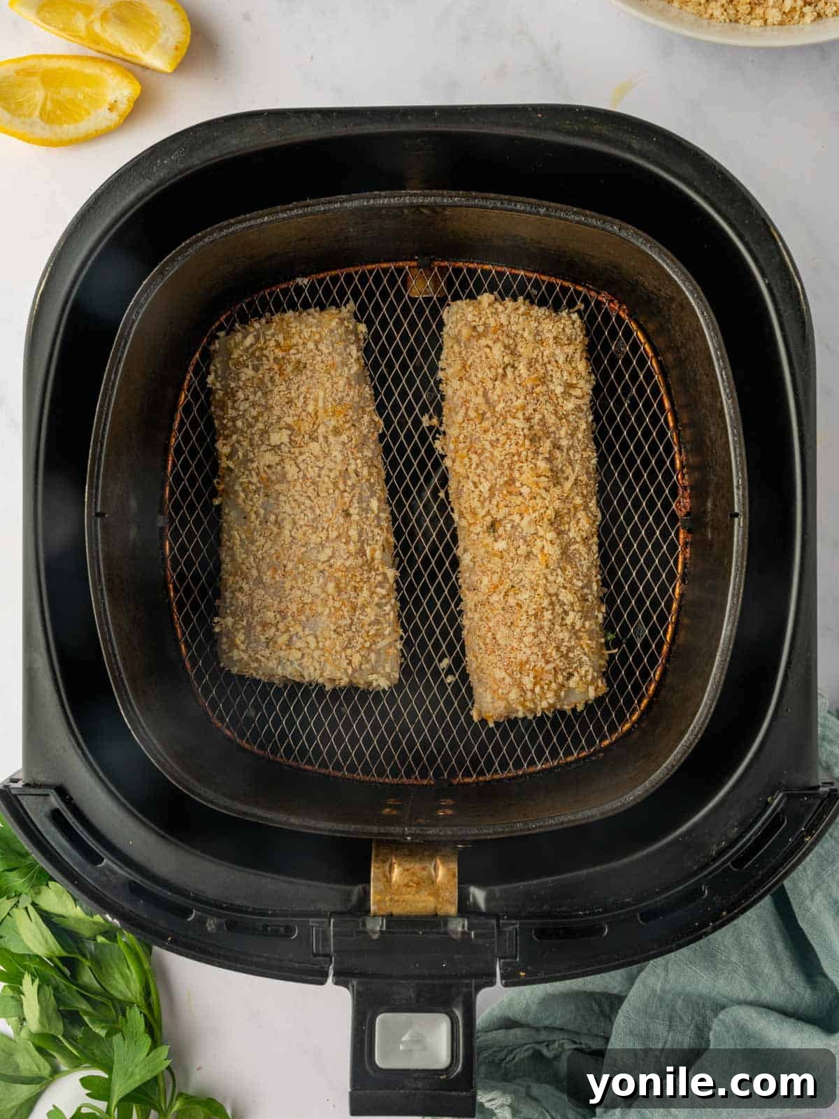 Breaded Mahi Mahi fish fillets arranged in a single layer inside the air fryer basket, ready to be cooked.