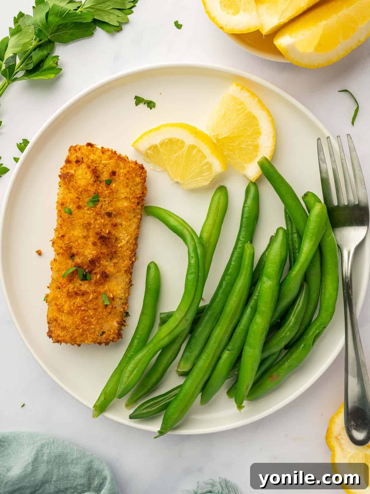 An air-fried mahi mahi fillet served on a plate alongside steamed green beans, offering a healthy and balanced meal.