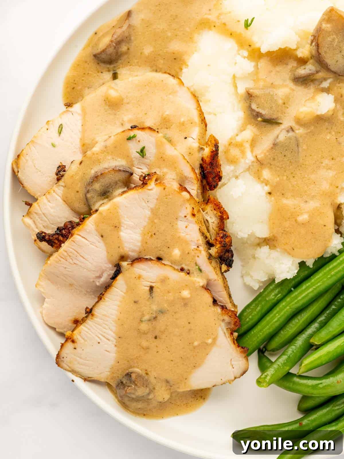 Generously sliced turkey breast, beautifully arranged and drenched in rich, savory gravy.