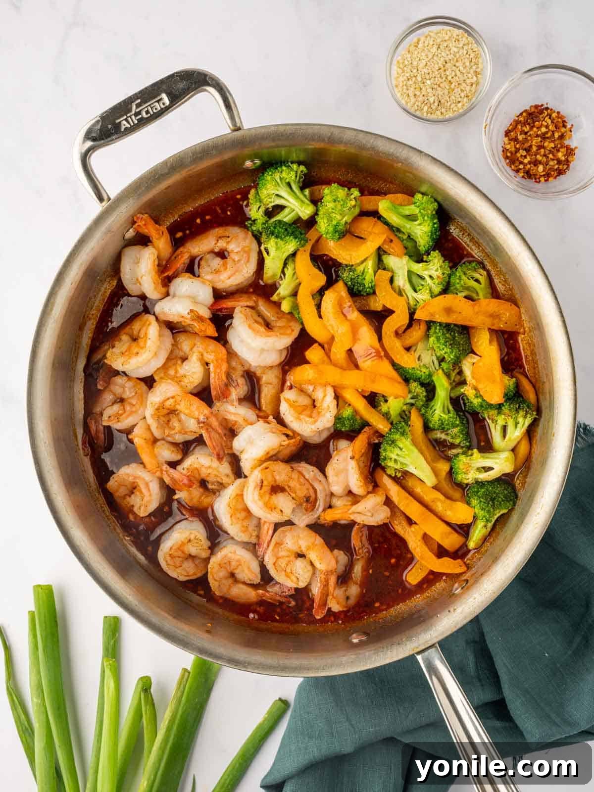 Sticky Sweet Chili Glazed Shrimp 7 Cooked shrimp and stir-fried vegetables being tossed with the sweet chili sauce in a skillet.